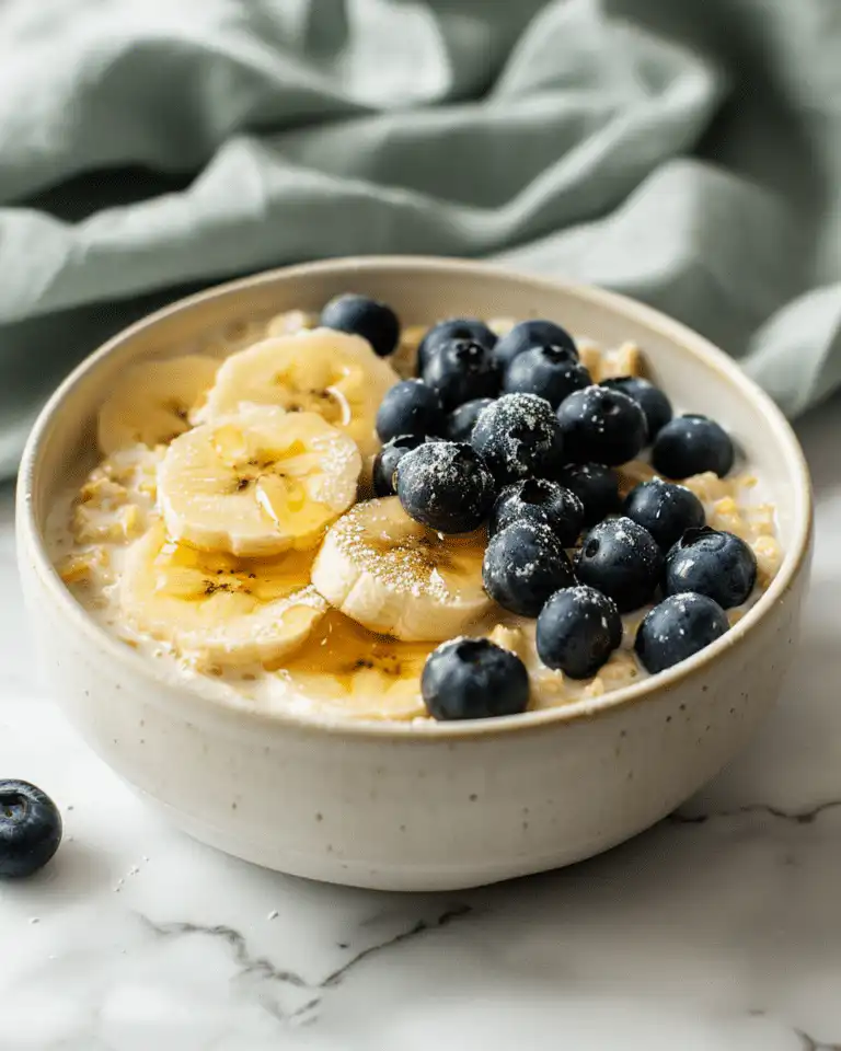 Beautiful Low FODMAP Rice Krispies breakfast bowl topped with fresh blueberries and banana slices in a white bowl