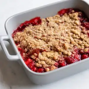 Low FODMAP strawberry and rhubarb crumble on a white plate — IBS-friendly dessert recipe