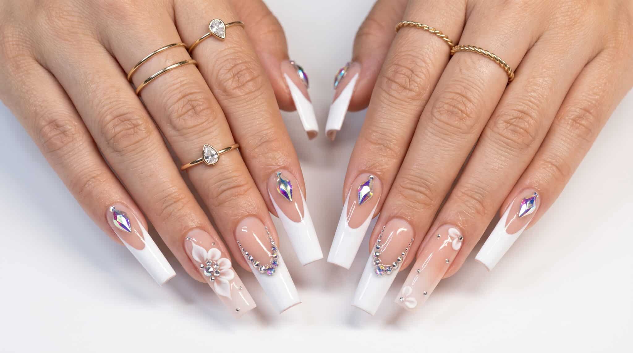 Clear acrylic press-ons with white 3D floral accents, rhinestones, and long transparent tips.