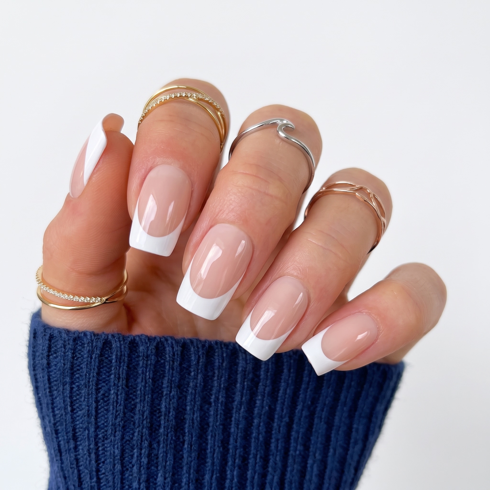 White and gold acrylic press-ons with floral accents, rhinestone details, and long almond tips.