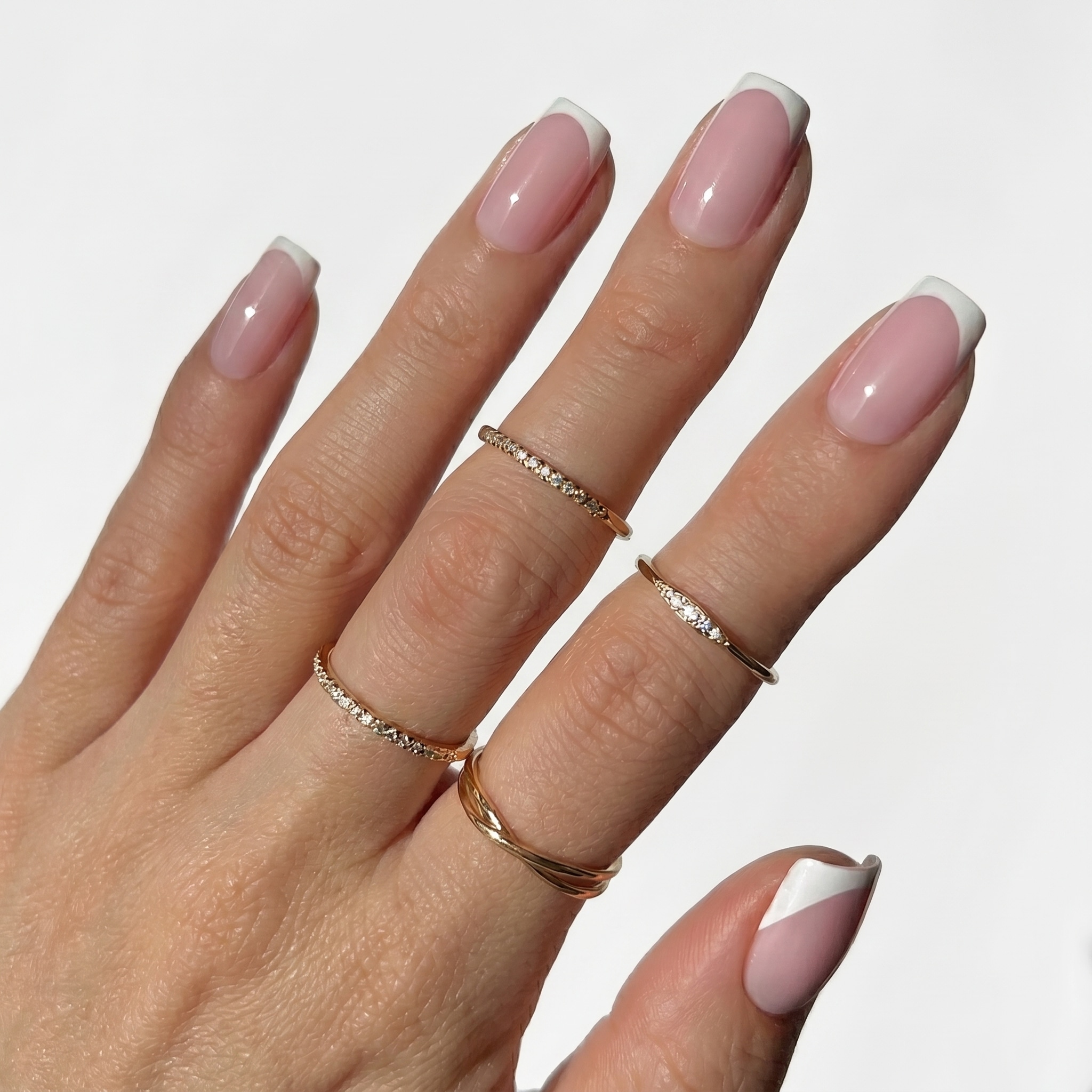 Soft nude almond nails with slim white French tips and a glossy finish