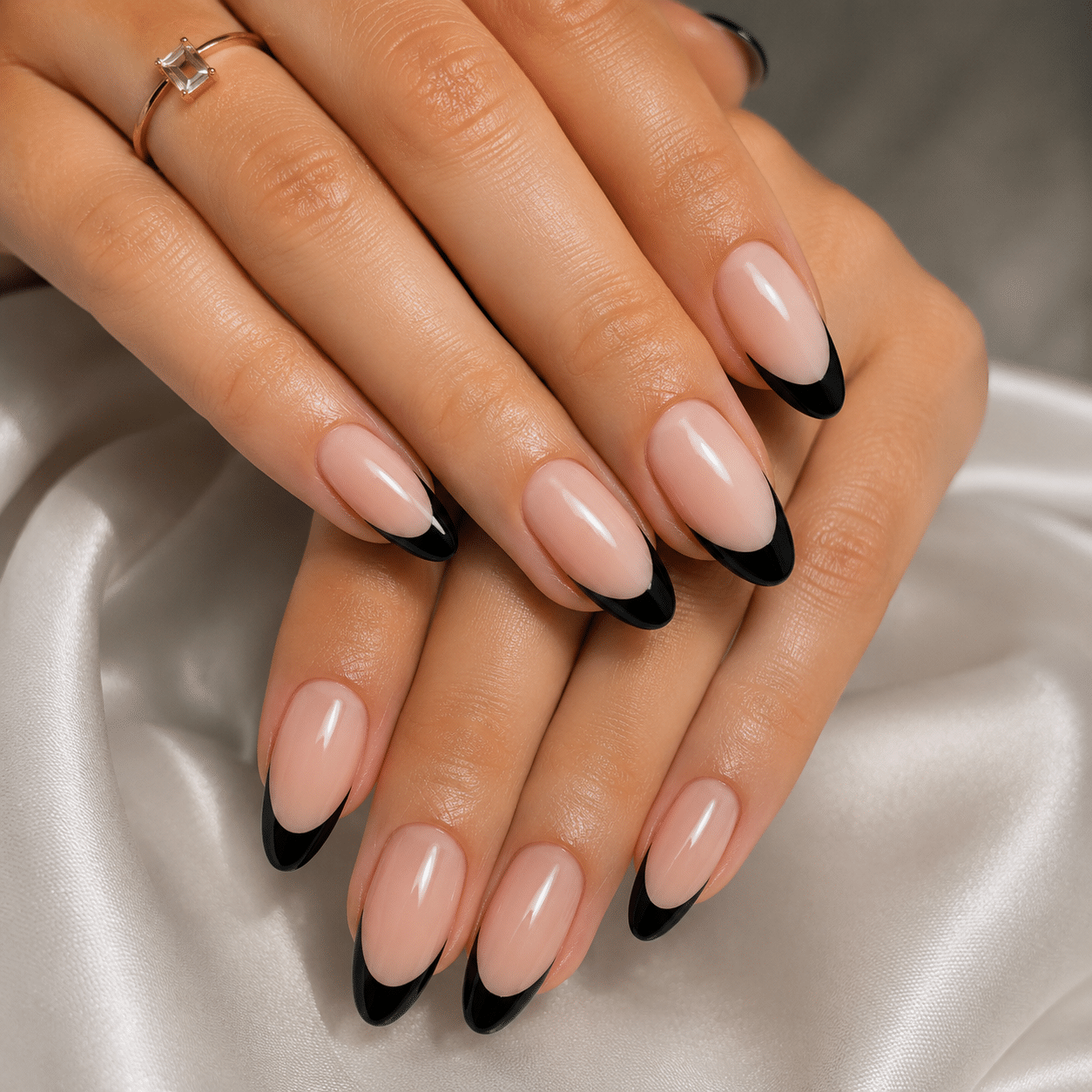 Clean nude nails with thin black French tips and a glossy finish
