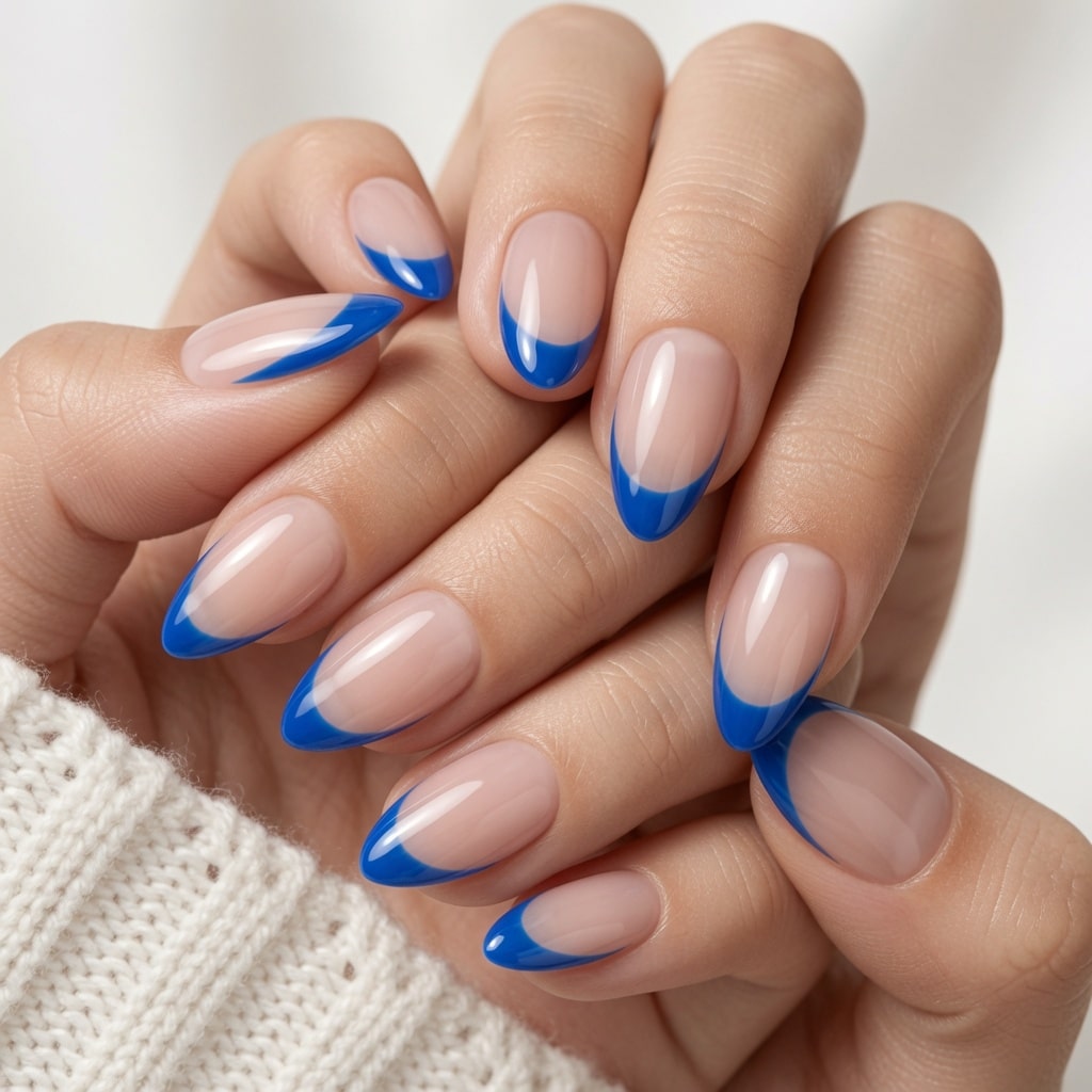Long nude nails with pale blue French tips and blue-and-white decorative accents on two hands.
