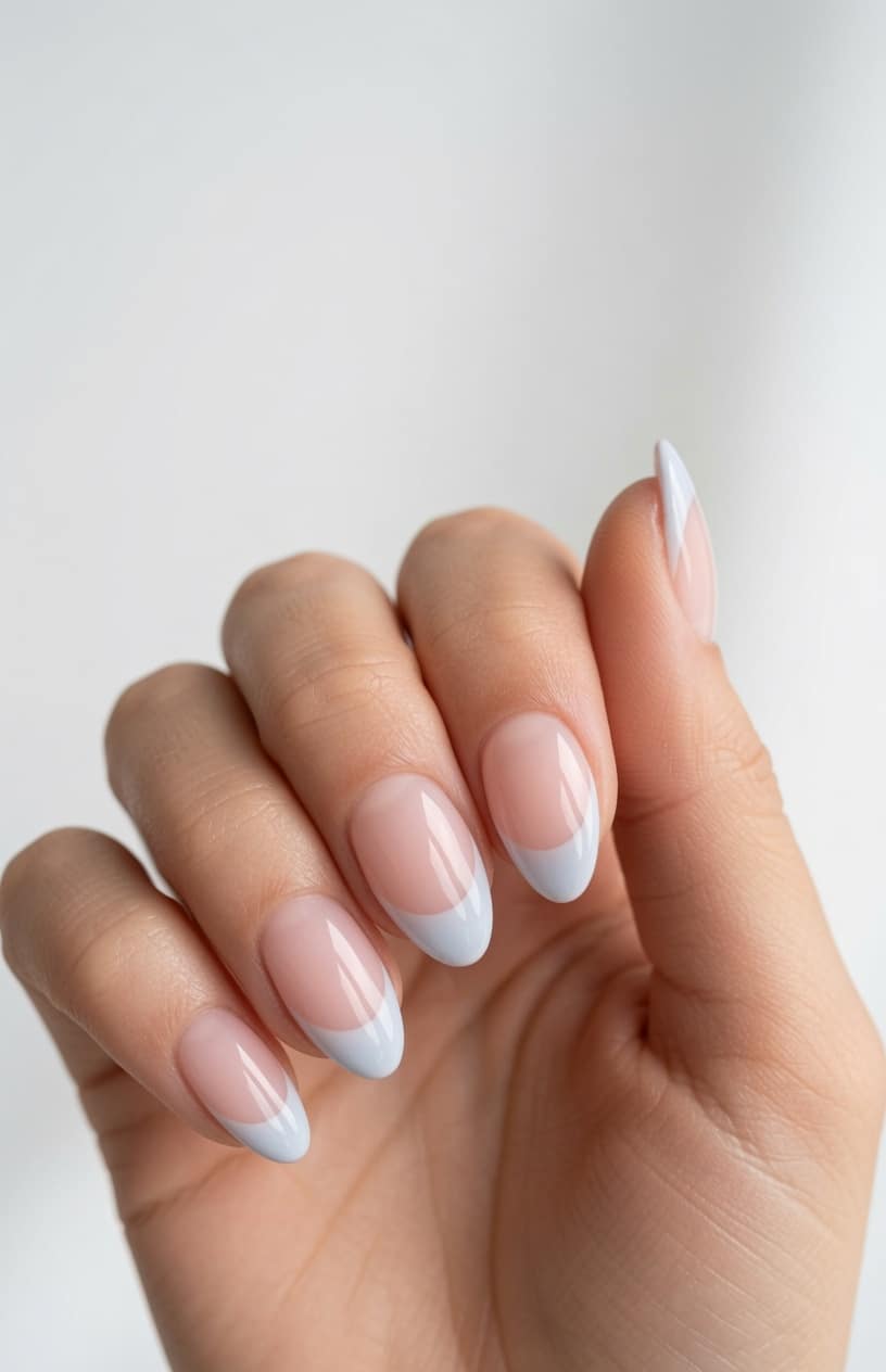 Two hands with nude almond nails and curved cobalt blue French tips.