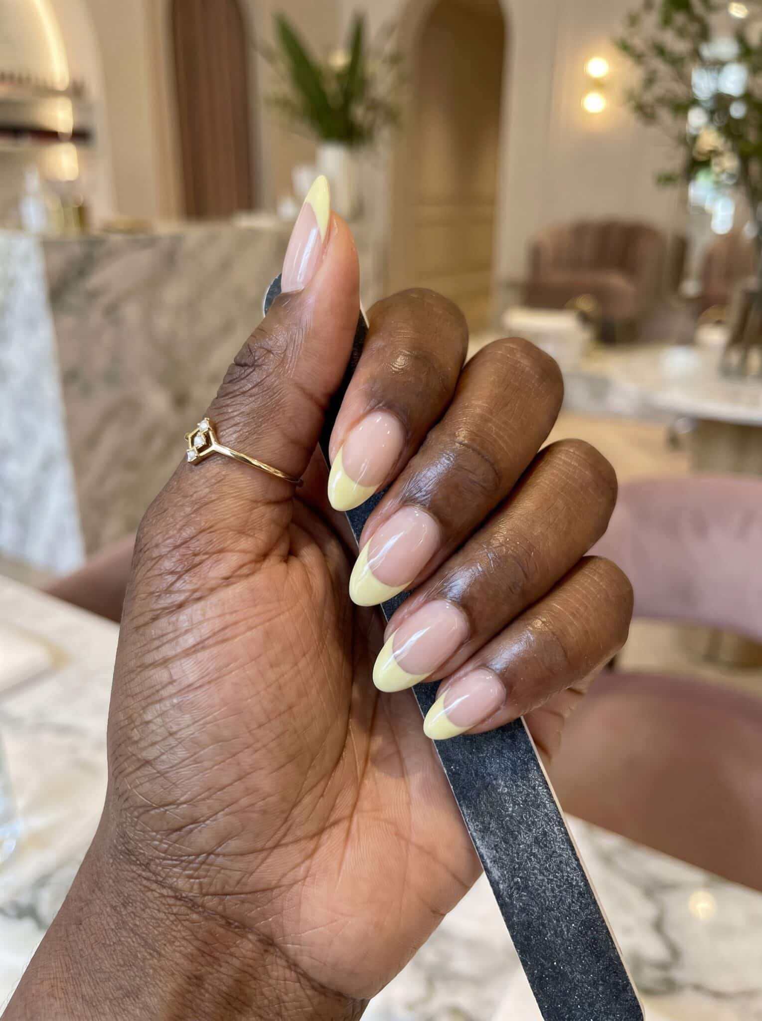 Pastel French tip nails shown with a brush as a clean manicure process reference