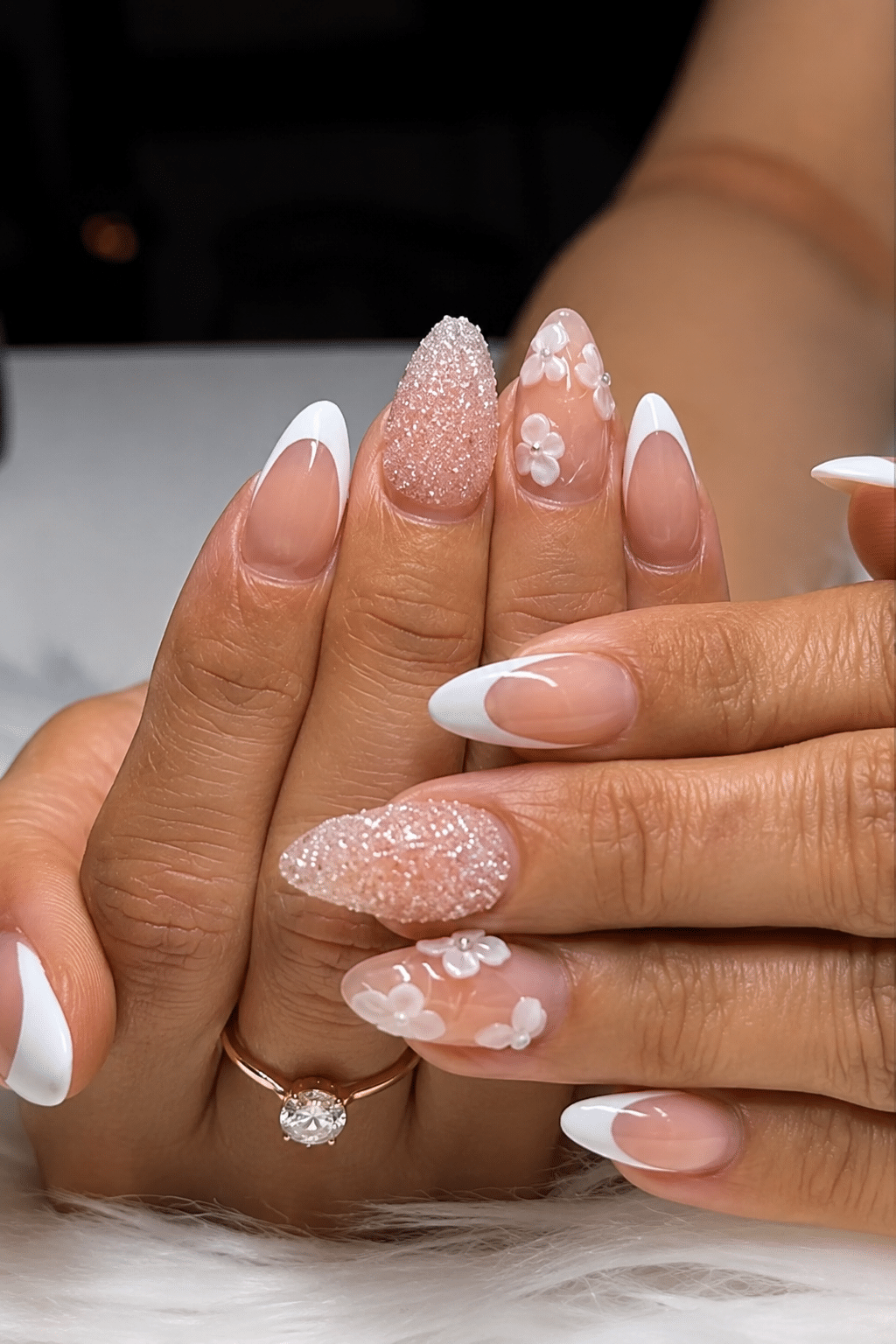 Decorated acrylic almond French tip nails with soft white details and a glossy nude base.