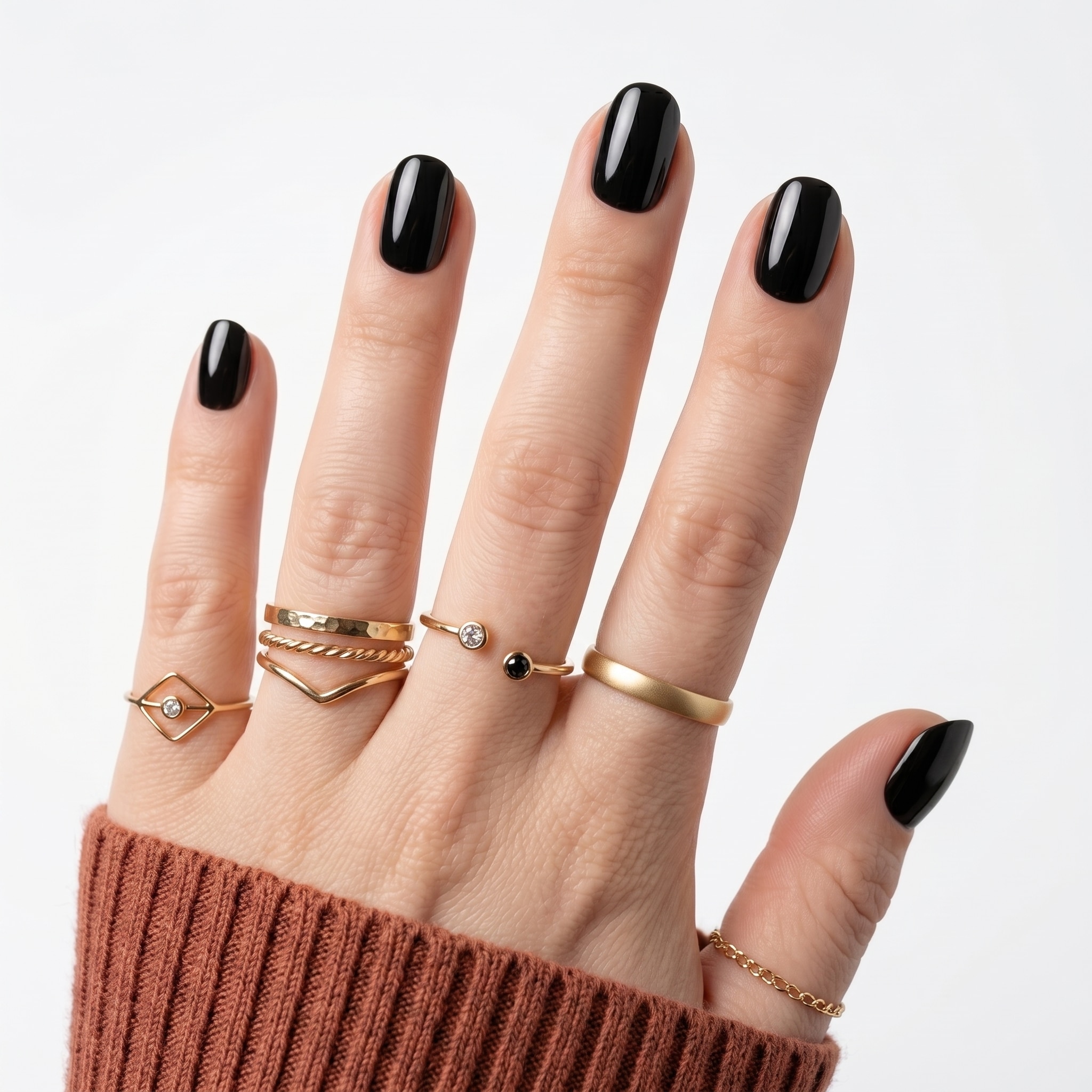 Glossy black extra short press-ons on both hands with a clean rounded shape and gold rings.