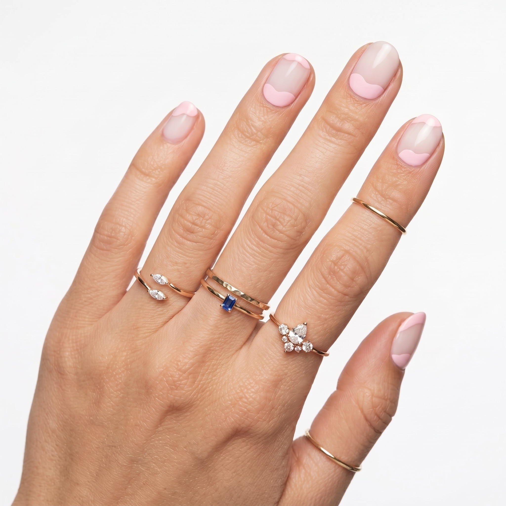 White extra short press-ons on deep skin tone with a glossy square finish and delicate rings.