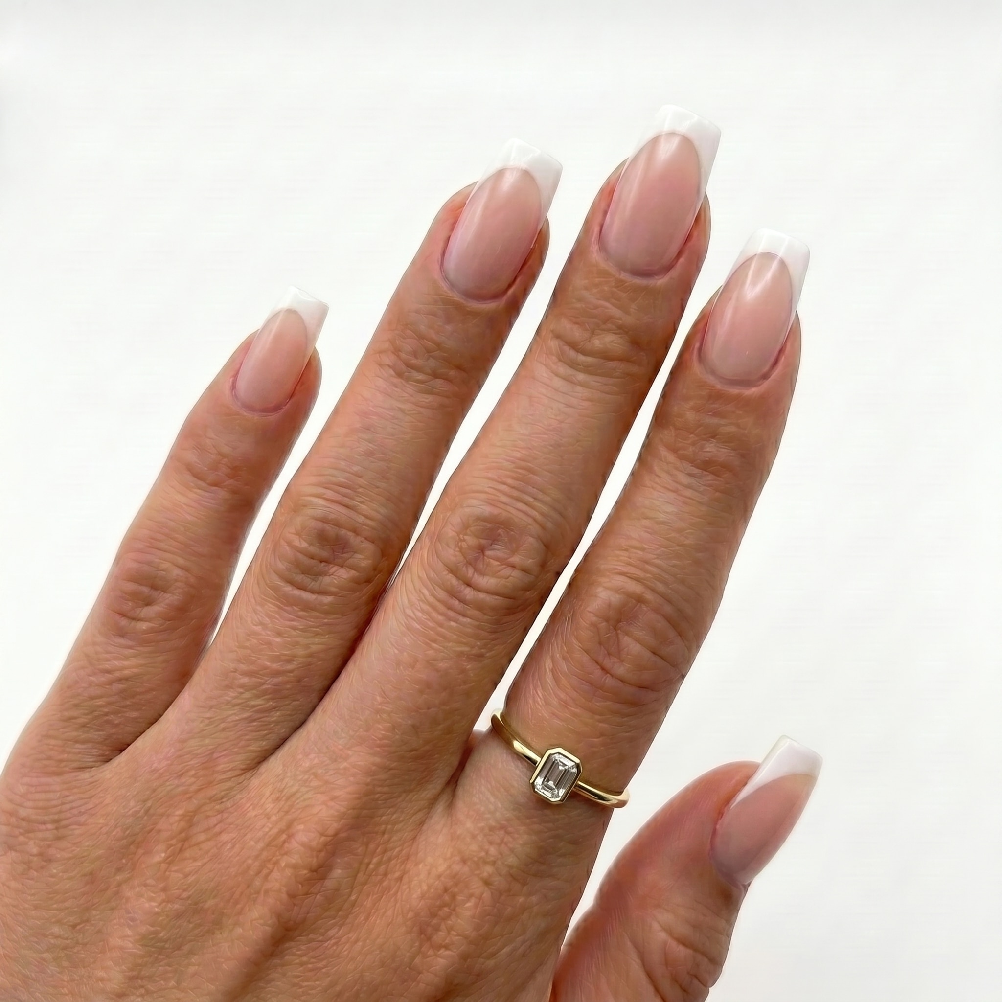 White French tips on nude almond nails against deep skin tones