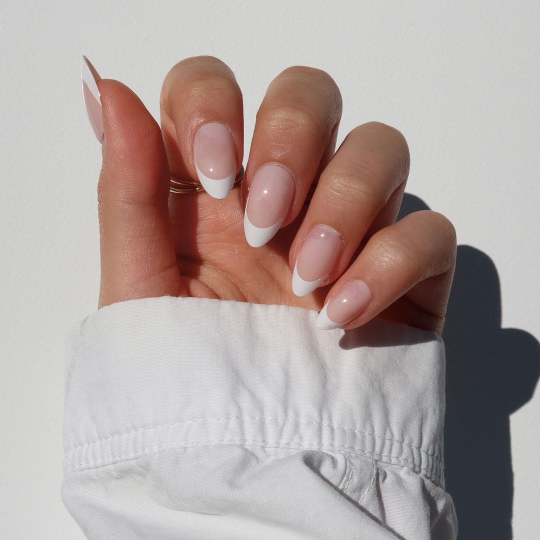 French tip press on nails with short square white tips, glossy nude base, and soft green sleeve styling.