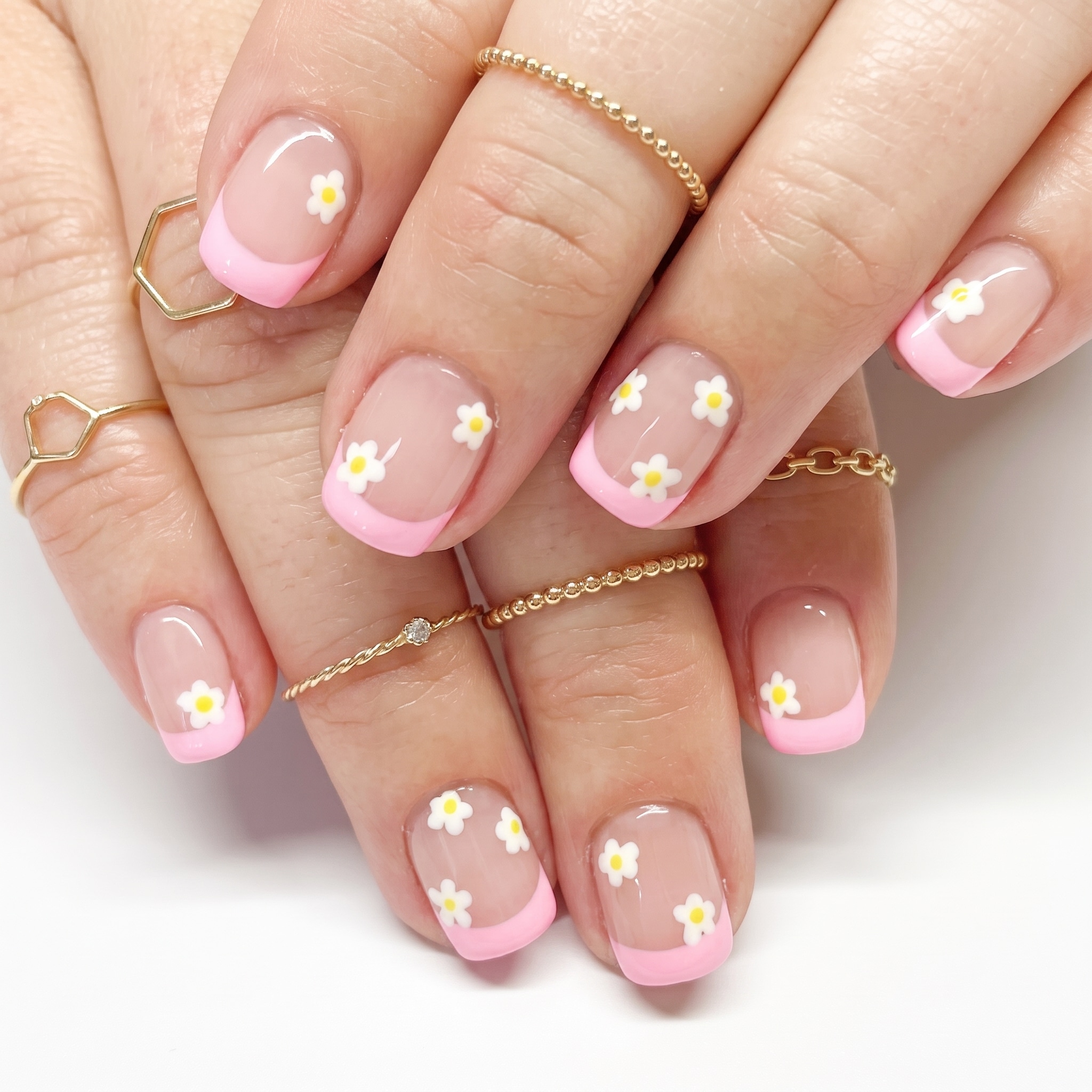 French press-ons with white tips, glossy pink bases, and delicate floral accent nail art.