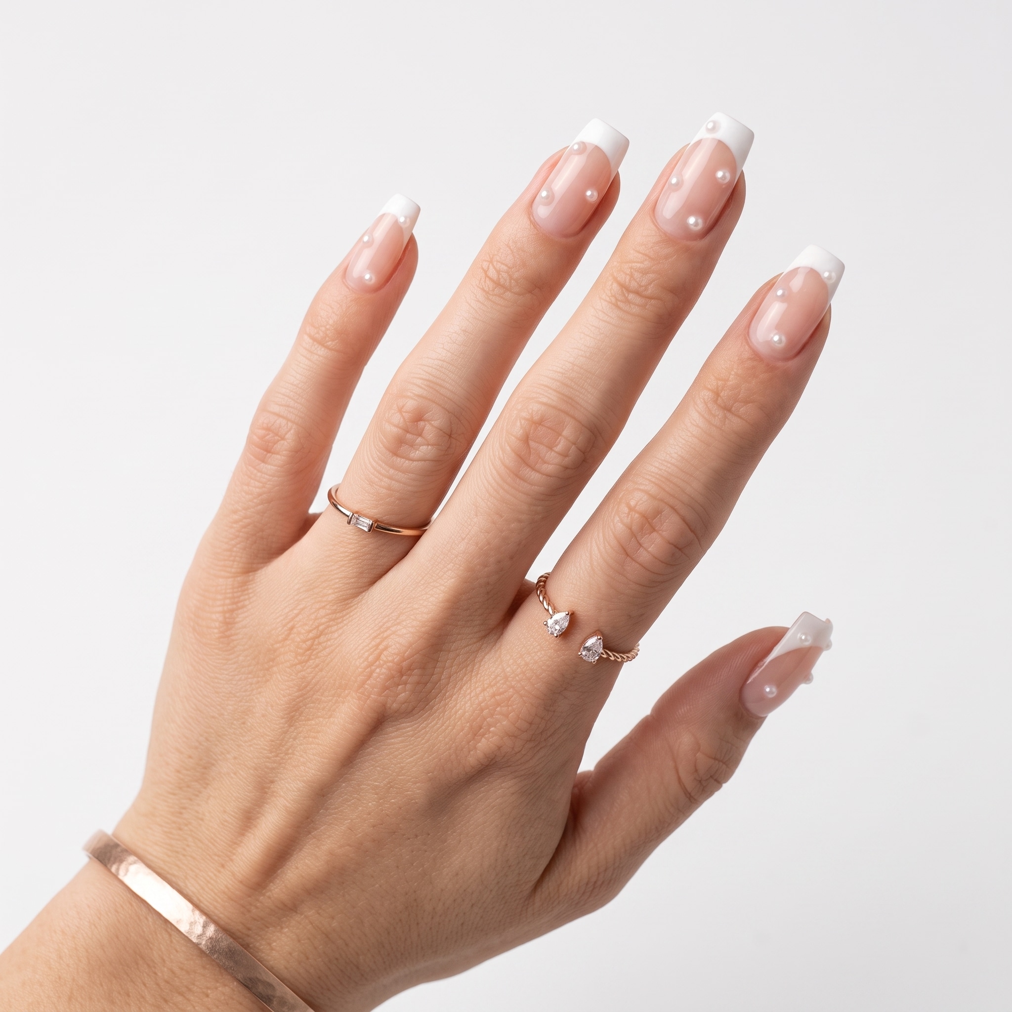 White French press-ons styled with a warm rust sweater sleeve and slim gold rings.