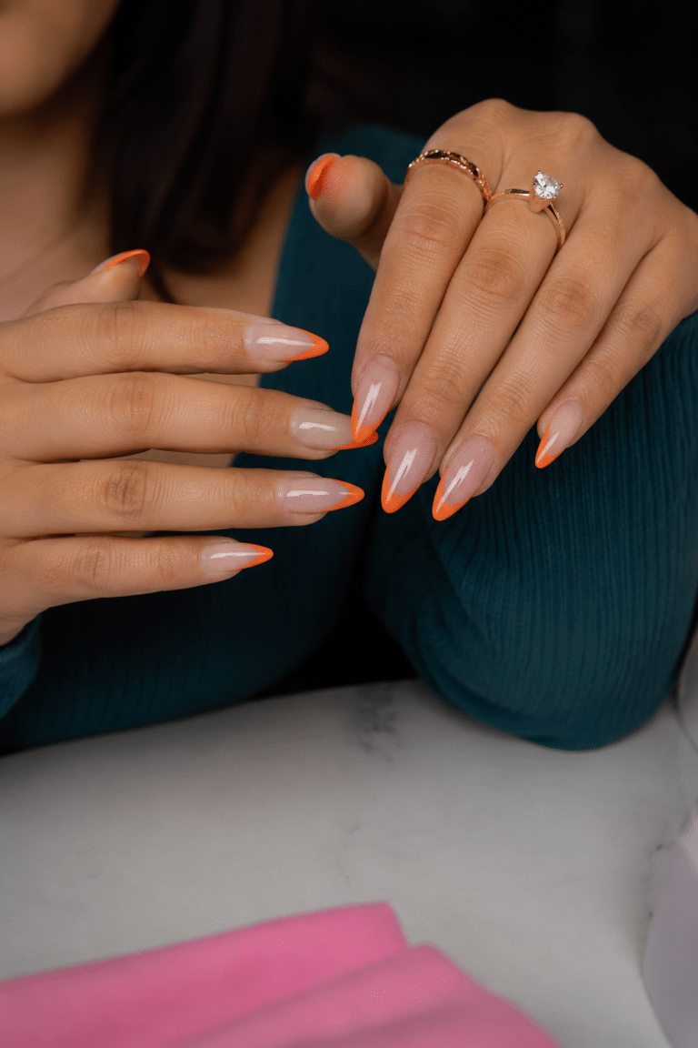 Orange almond French tip nails with a clean nude base and bright orange tips