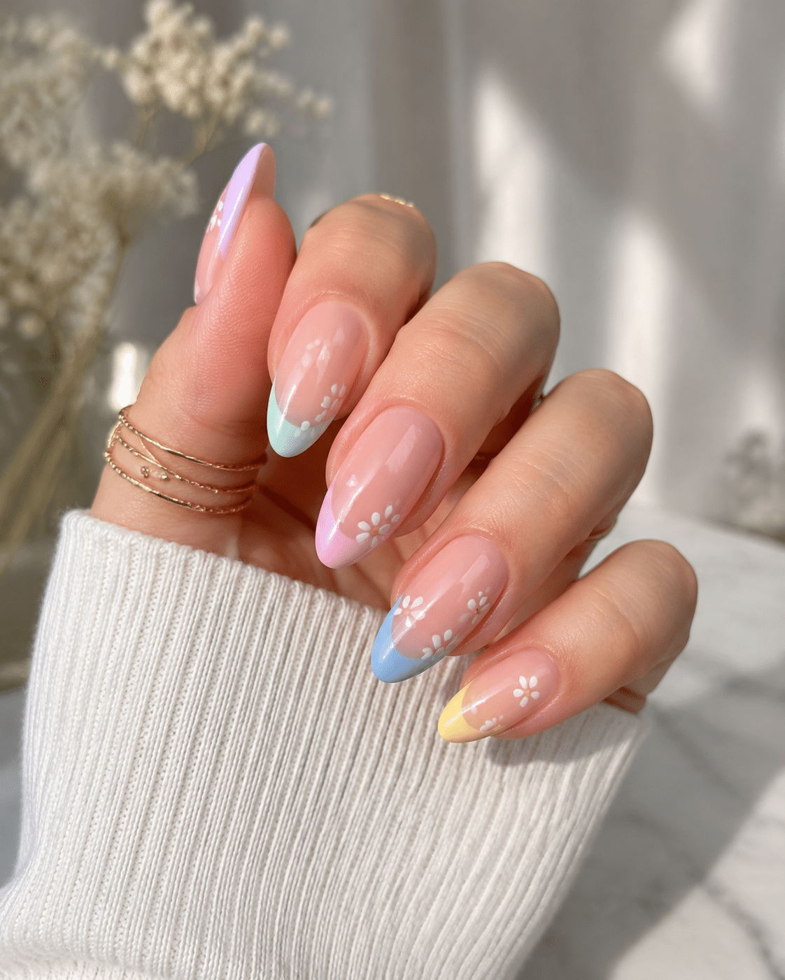 Pastel French tips on almond nails with a glossy nude base