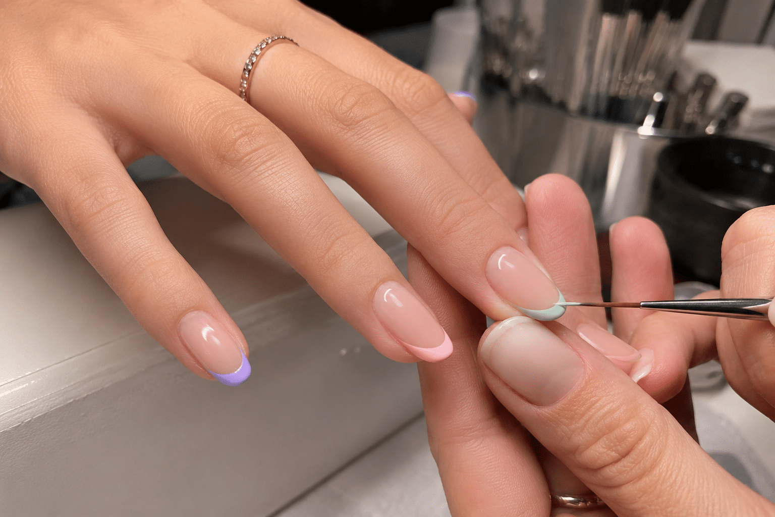 Step by step French manicure process with detail brush painting a pink French tip