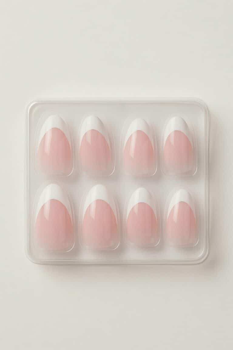 Elegant hand wearing pink French tip press on nails resting on a white sleeve.