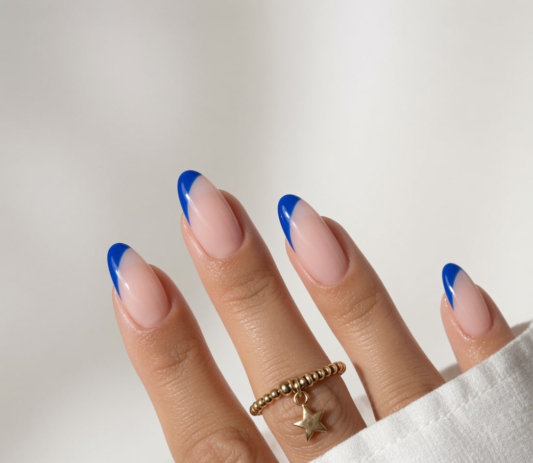 Short nude nails with vivid blue French tips.