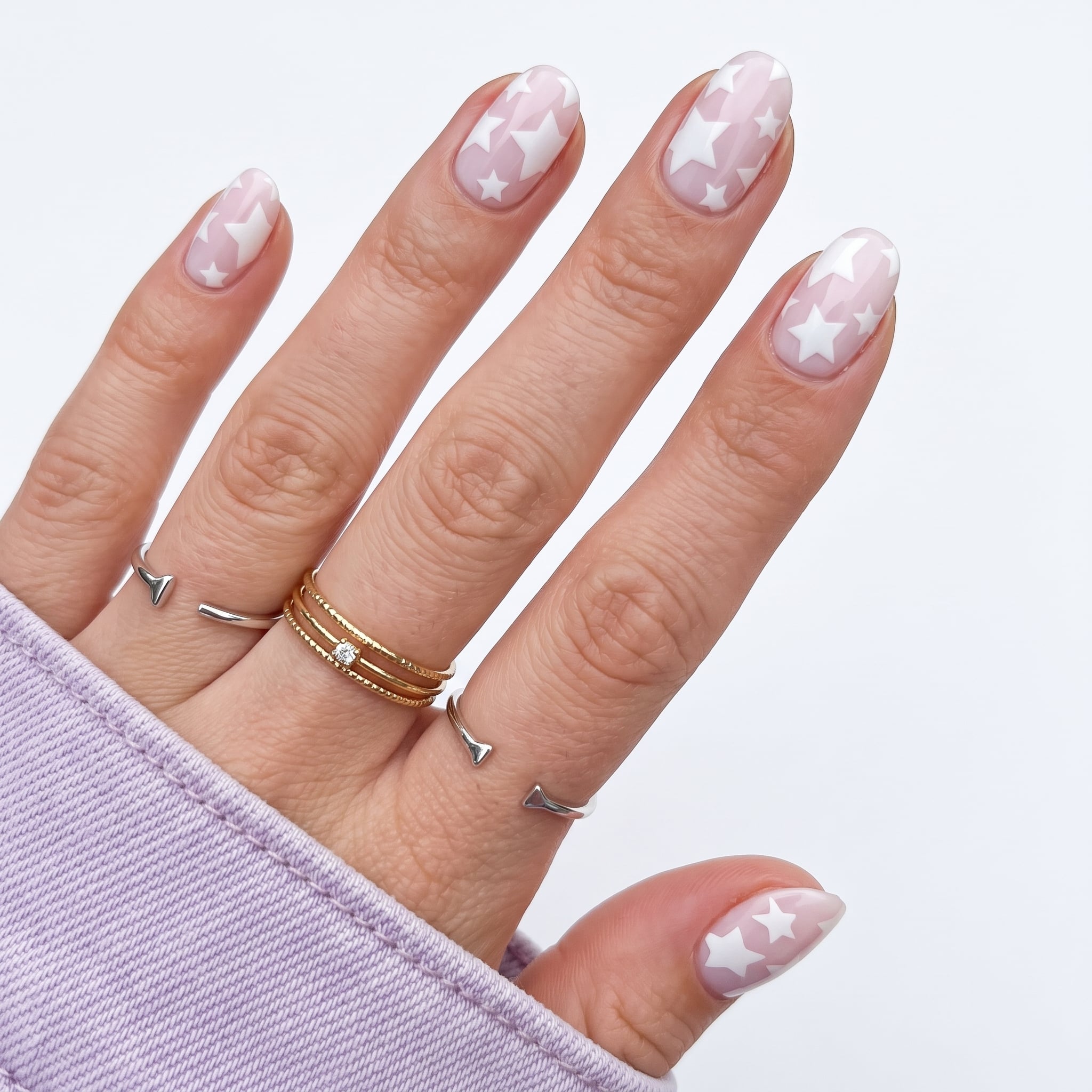 Glossy pink short press-on nails on a hand in soft natural light
