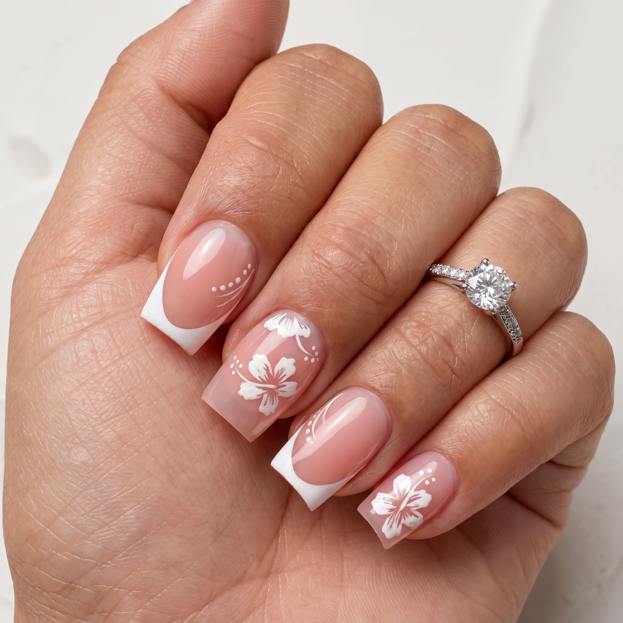 Simple square French tip nails with a glossy nude base and soft floral accents