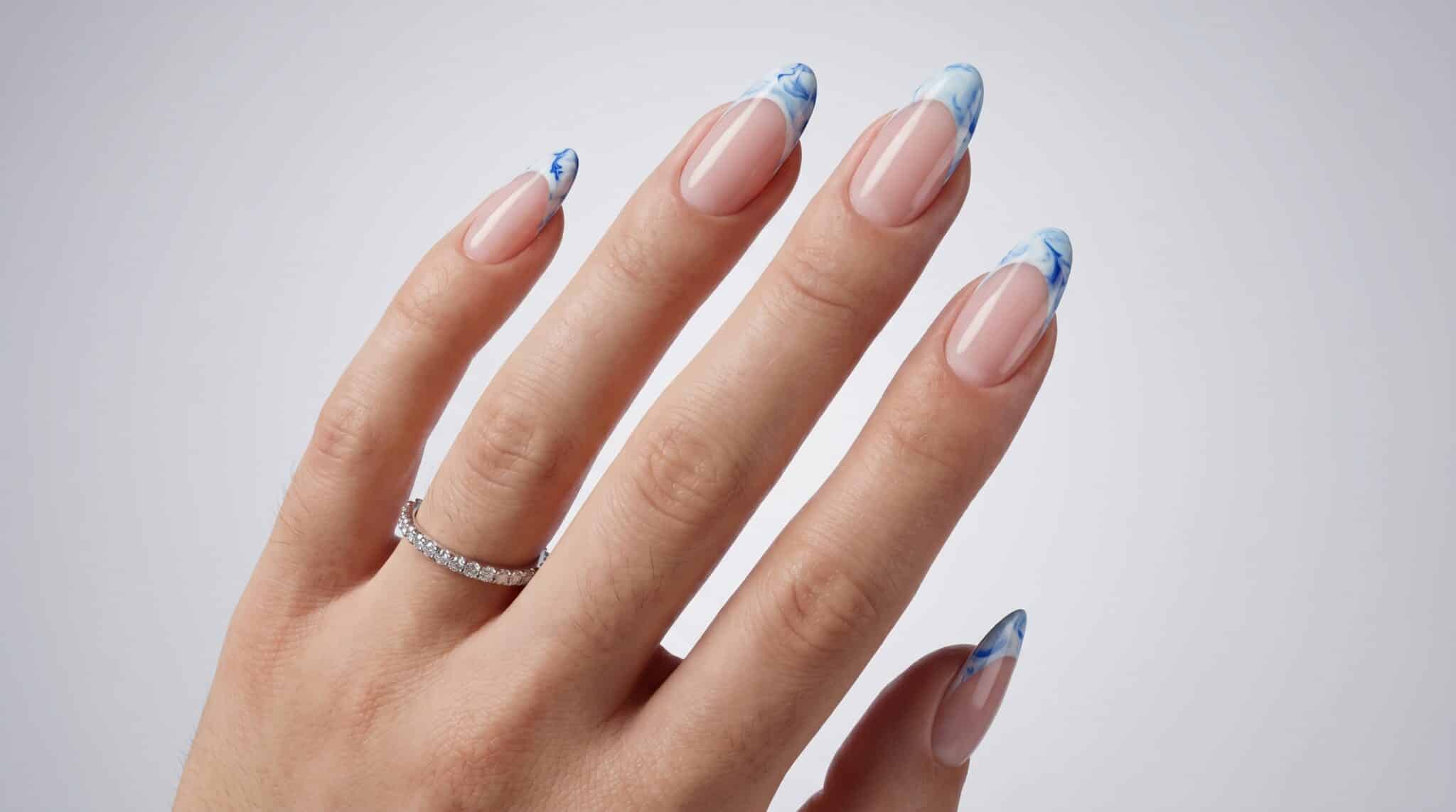 Short blue French tip nails with a clean nude base and glossy finish