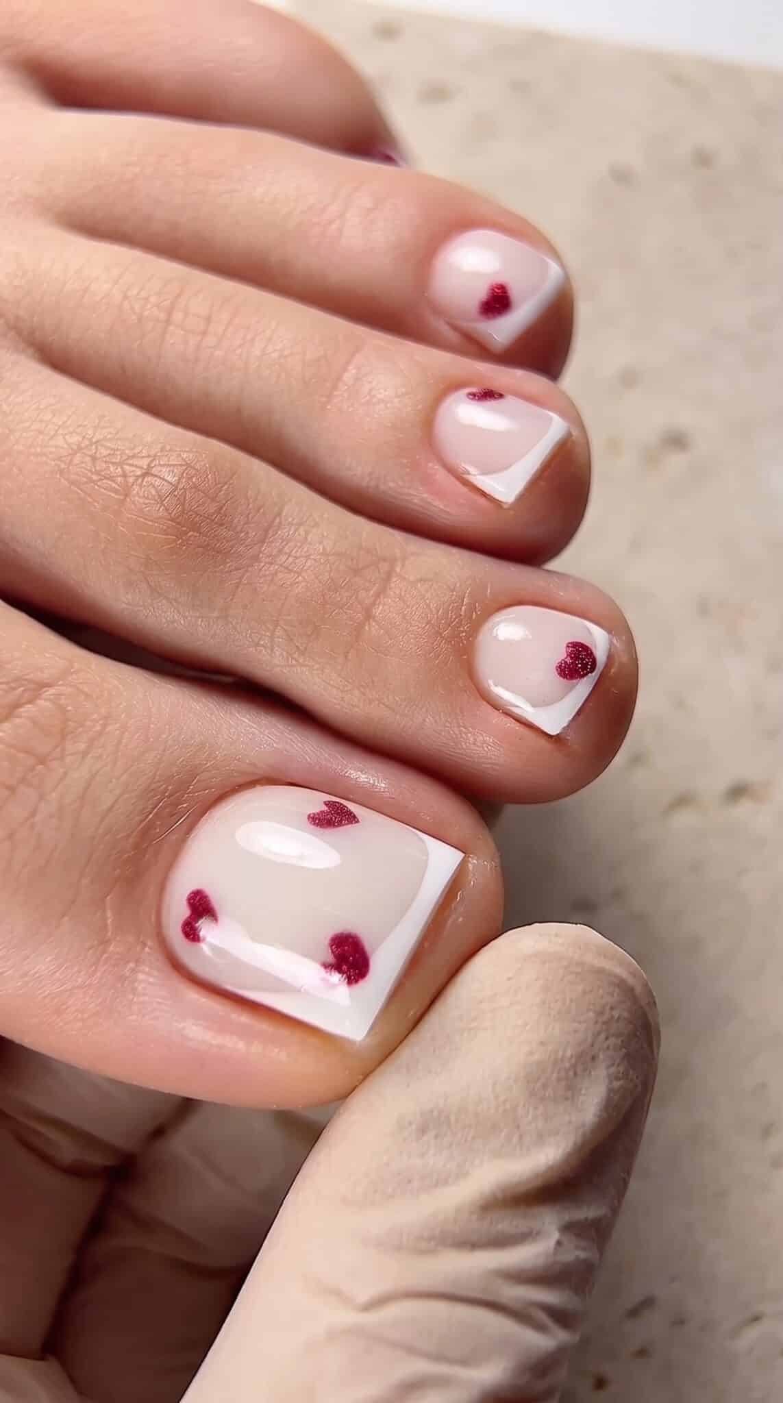flirty french tip toes with pink heart detail and glossy pedicure finish