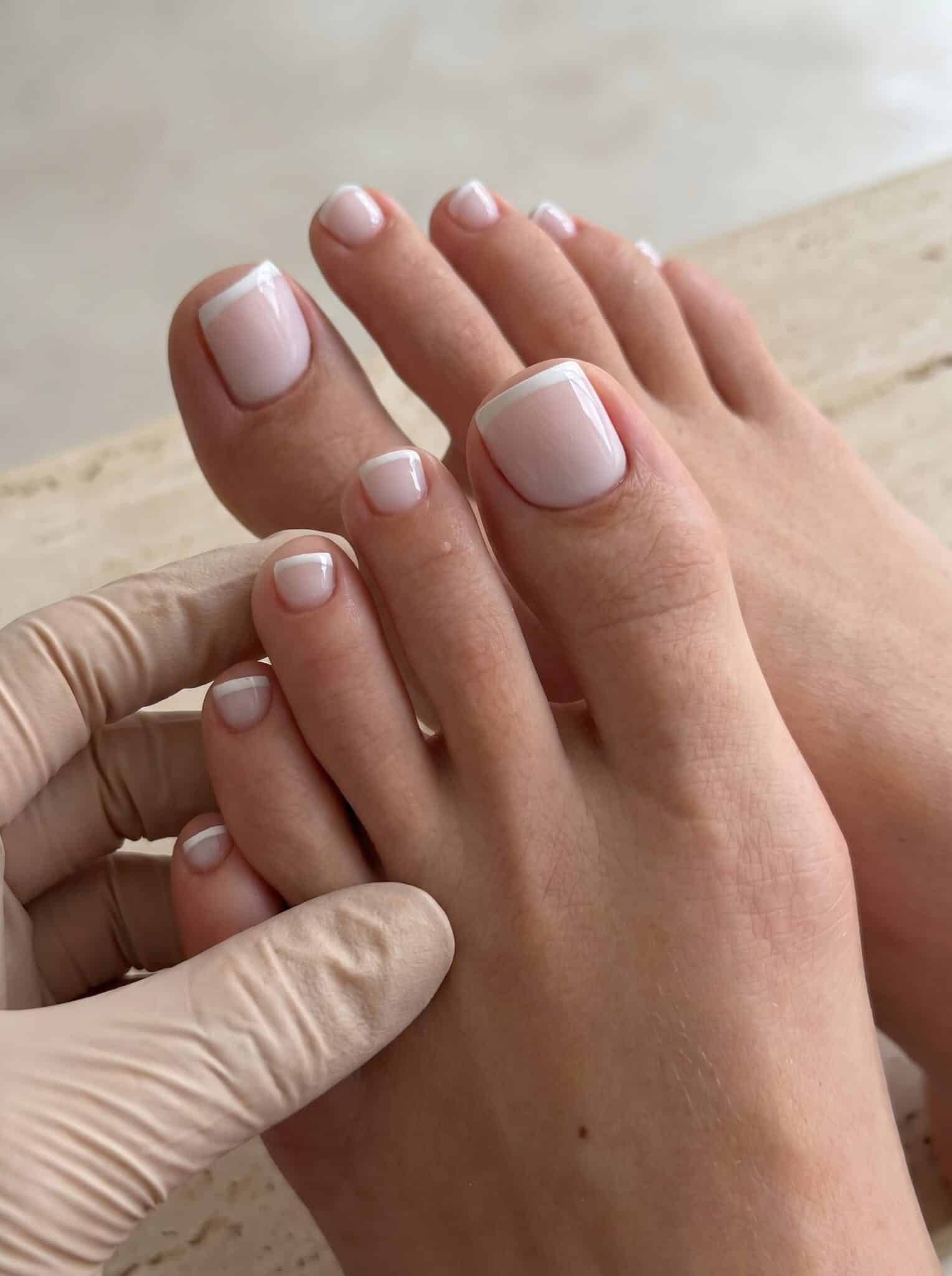 salon french tip pedicure with clean white tips and glossy toenail finish