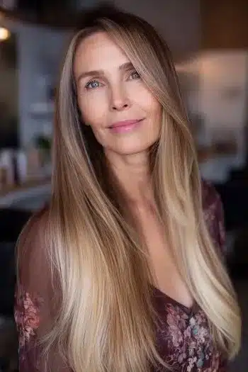 Balayage highlights on a side-parted style, one of 30 inspiring long hairstyles for women over 50 with fine hair.