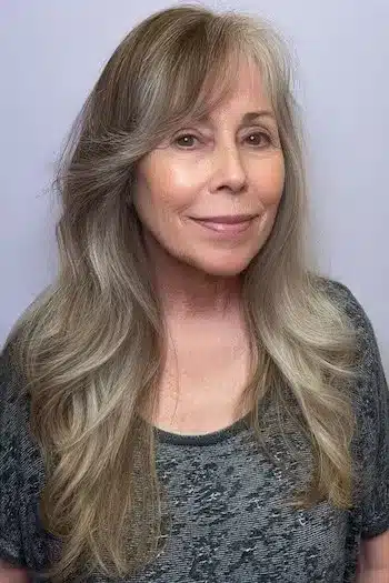 Side-swept bangs with layered waves, one of 30 inspiring long hairstyles for women over 50 with fine hair.