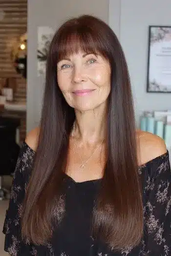 Classic long hair with a full fringe, included in 30 inspiring long hairstyles for women over 50 with fine hair.