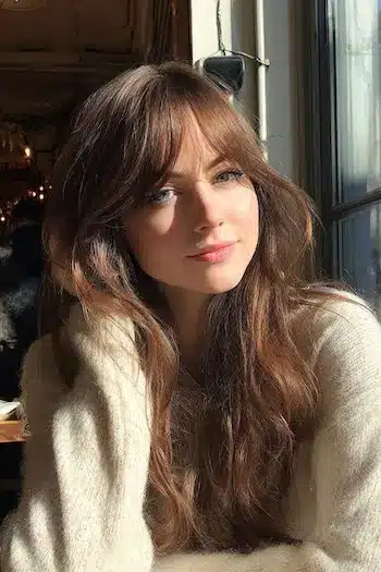 A model showcasing long natural waves with curtain bangs, one of the 31 Hairstyles With Bangs That Prove A Little Fringe Goes A Long Way - Parisfy