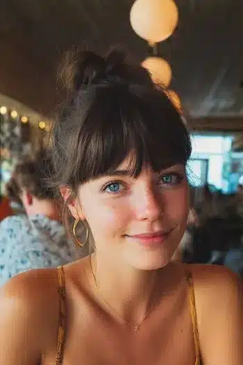 31 Hairstyles With Bangs That Prove A Little Fringe Goes A Long Way 20 A sleek high bun featuring a straight fringe, highlighting the 31 Hairstyles With Bangs That Prove A Little Fringe Goes A Long Way - Parisfy