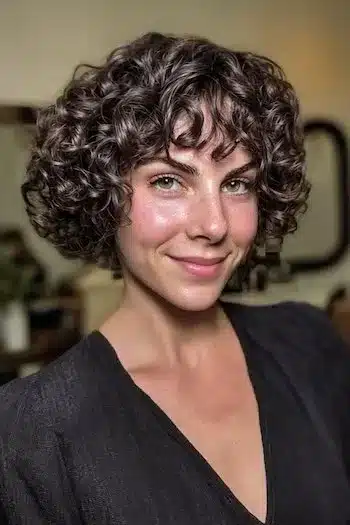 31 Hairstyles With Bangs That Prove A Little Fringe Goes A Long Way 28 Cropped curly cut featuring a straight fringe, part of the 31 Hairstyles With Bangs That Prove A Little Fringe Goes A Long Way - Parisfy
