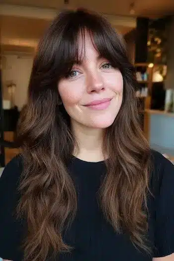 31 Hairstyles With Bangs That Prove A Little Fringe Goes A Long Way 29 Long flowing waves with wispy curtain bangs, showcasing the 31 Hairstyles With Bangs That Prove A Little Fringe Goes A Long Way - Parisfy