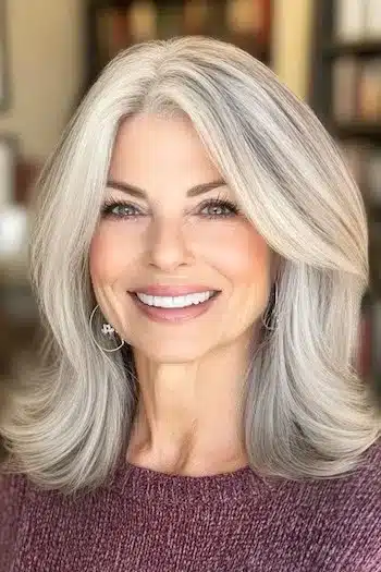 Long Bob with Layers and Flipped-Up Ends Haircut on a smiling woman with gray hair.