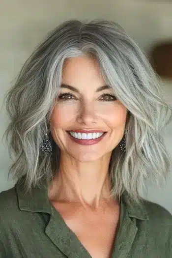 Tousled Textured Waves with Subtle Layers Haircut on a smiling woman with gray hair.
