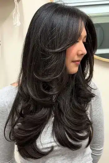 Long layered butterfly haircut on a woman with brown hair, showcasing soft layers and movement