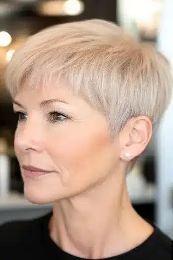 Brushed-forward thin fine pixie haircut for an older woman with short blonde hair