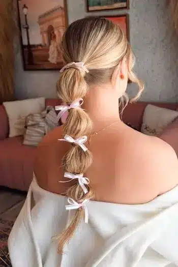 32 Fresh Summer Haircuts You’ll Want To Try This Season 3 Back view of a bubble ponytail with ribbon bows on long blonde hair