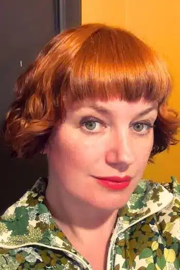 Textured French bob with natural waves on a woman with bright copper red hair