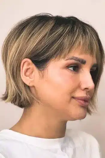 Textured French bob with blunt ends on a woman with brown hair with blonde highlights, side view