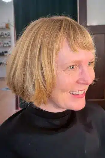 Rounded classic French bob on a woman with blonde hair, side view
