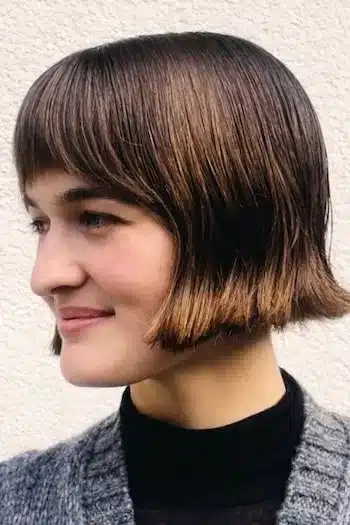 Sleek French bob with tapered ends on a woman with brown hair with soft highlights, side view