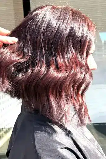 Dimensional mahogany wavy long bob with rich color depth, side view
