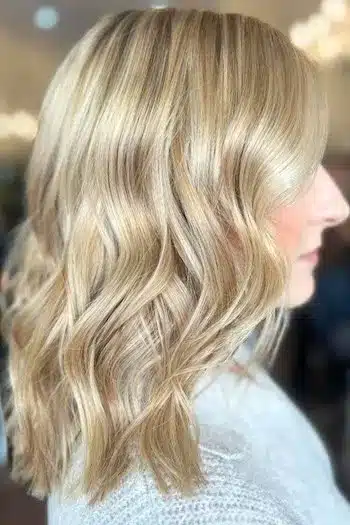 Long blonde wavy bob with soft, flowing waves, side profile