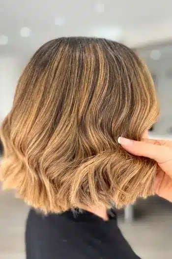 Caramel highlighted wavy bob with warm, golden tones, side profile