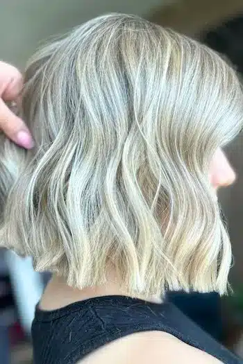 Icy blonde wavy blunt bob with a cool, platinum finish, side view