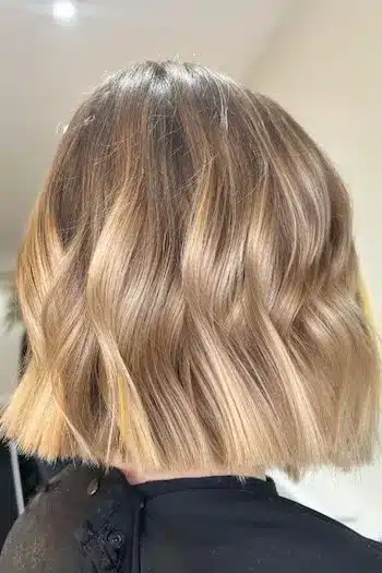 Blunt-cut wavy bob with blonde balayage highlights, back view