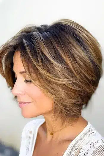 Balayage layered wedge haircut with warm brown and blonde tones, side view