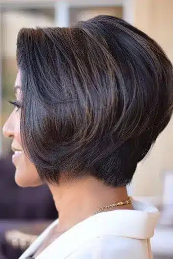 Rounded layered wedge haircut in dark brown, side view of a smiling woman
