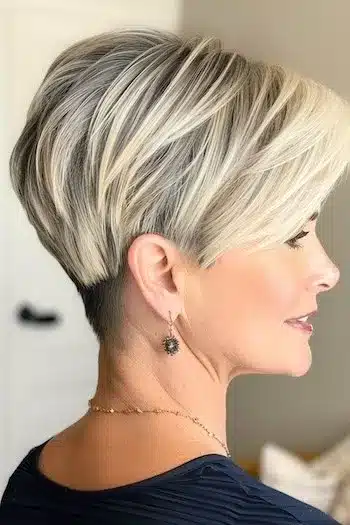 Platinum blonde wedge haircut, side profile of a smiling woman with cool tones